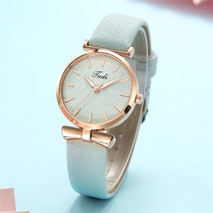 Close-up of light blue leather strap watch with rose gold leaf pattern dial and bow charm