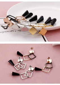 Detailed view of geometric dangle earrings with metallic squares and black cone pendants