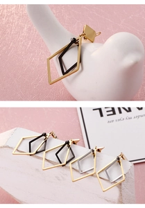 Macro detail of geometric rhombus pendant earrings in polished gold and black finish