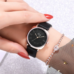 Detail of minimalist black leather watch with rose gold case and sparkling zircon bracelet