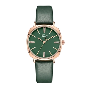 Close-up of rose gold square watch case with green dial and sparkling diamond markers