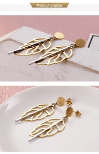 Detail of gold hollow leaf earrings with silver metal bar and dual-tone metallic texture