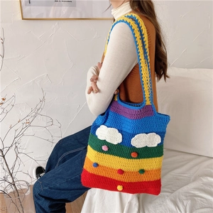 Rainbow knit tote bag with cloud and pompom details worn on a woman's shoulder