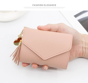 Close-up of pink litchi grain leather wallet with tassel and heart pendant charm