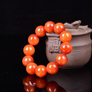 Macro detail of 20mm amber wood beads with orange-red gloss and traditional tea jar