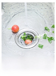 Close-up of fine mesh kitchen sink filter bag catching food residue under running water