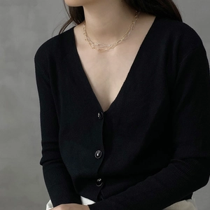 Detail of minimalist gold double-layer chain necklace on black V-neck ribbed cardigan