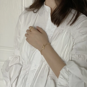 Detail of gold OT buckle chain bracelet paired with minimalist ring on female model