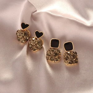 Close-up of geometric earrings with black enamel and grey rhinestones on silk