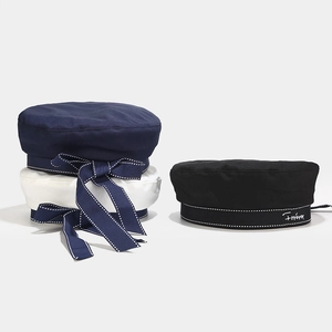 Detail of nautical cotton berets with dot trim and embroidered bow ribbons