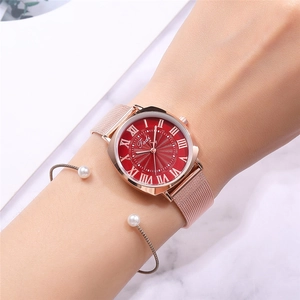 Detail of rose gold mesh watch with red sunray dial and pearl bracelet on marble