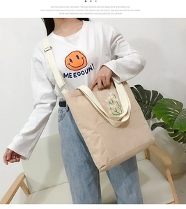 Detail of beige corduroy tote bag with daisy embroidery and cotton strap on model