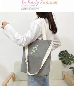 Close-up of gray corduroy tote bag with daisy embroidery and adjustable strap