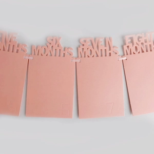 Close-up of pink baby monthly photo banner with hollow lettering from five to eight months