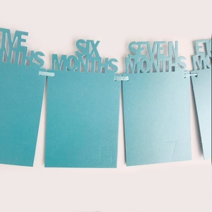 Close-up of laser-cut blue cardstock banners for baby first year growth milestones