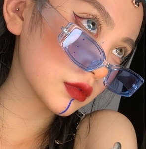 Close-up of blue transparent rectangular sunglasses on a model with Y2K style makeup