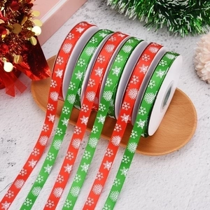 Red and green Christmas ribbons with snowflake patterns on a rustic wooden tray