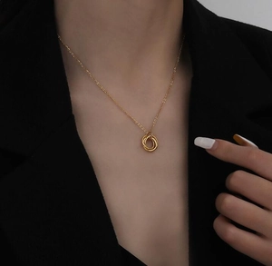 Close-up of 18K gold triple interlocking ring necklace worn on elegant black attire