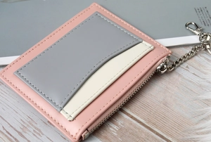 Detail of pink and gray patchwork wallet featuring card slots and a metal chain