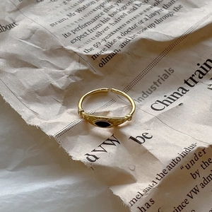 Vintage gold adjustable ring featuring a black oval stone on retro newspaper background