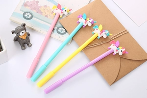 Close-up of four colorful unicorn gel pens with 3D silicone toppers on a desk
