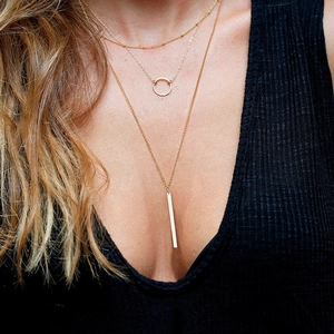 Close-up of triple-layered gold-plated stainless steel necklaces with geometric pendants