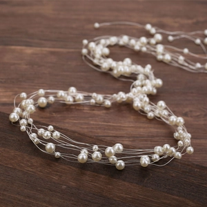 Détail de bijoux de tête de mariée faits main avec des perles blanches sur bois rustique