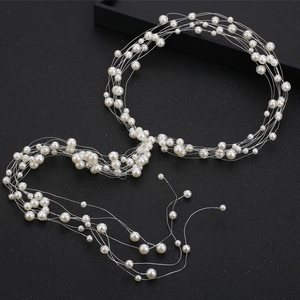 Détail d'un ensemble de bijoux de mariée avec des perles blanches sur un fil d'argent fin