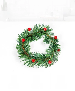 Detail shot of PVC pine needles and red berries on a festive Christmas candle wreath