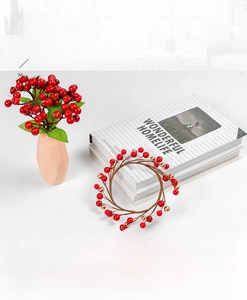 Detail of red Christmas berry wreath and matching faux floral set in a peach vase