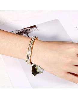 Dettaglio dell'elegante bracciale a polsino dorato con doppia fila di strass al polso