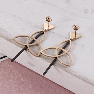 Rose gold geometric triangle drop earrings with black vertical bars on wood background