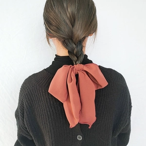 Elegant rust red bow hair scrunchie with long ribbons on French braid hairstyle
