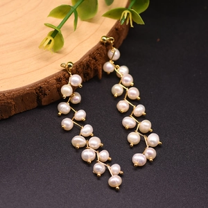 Detailed macro view of handmade long pearl drop earrings with 18k gold-plated branch design