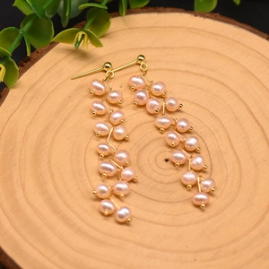 Close-up of long natural freshwater pearl drop earrings on a rustic wood background