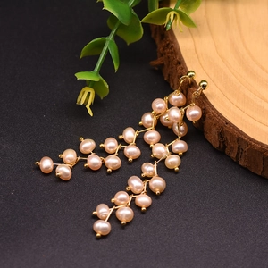 Detail of long drop earrings featuring natural freshwater pearls and 18k gold plating