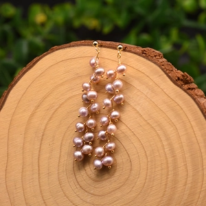 Macro shot of long natural lavender pearl dangle earrings on rustic wood grain