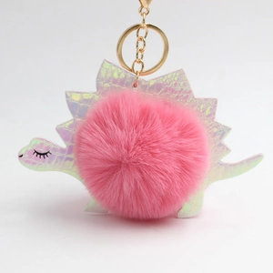 Portachiavi dinosauro in pelle PU iridescente con pompon rosa su sfondo bianco pulito