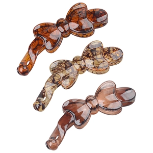 Three bow-shaped amber and tortoiseshell resin banana hair clips on white background
