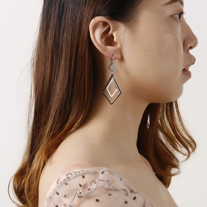 Minimalist silver geometric titanium steel hoop earrings worn on a model's left ear