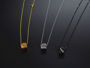 Close-up of gold, silver, and black titanium steel dice pendant necklaces on black background