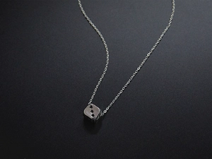 Macro shot of silver dice pendant with cross chain on a dark textured background