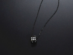 Close-up of minimalist black titanium steel dice pendant on matte background