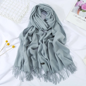 Detail view of sky blue cashmere scarf featuring soft fringes and a branded fabric label