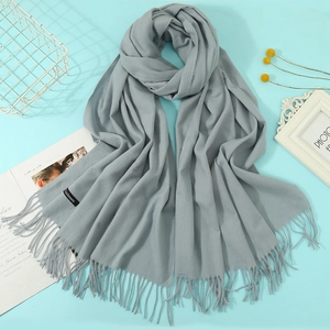 Detail of light blue cashmere scarf with tassels, styled with dry flowers and magazine