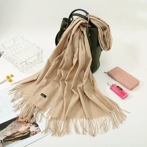 Detailed close-up of a camel cashmere winter scarf featuring fringe and a premium label
