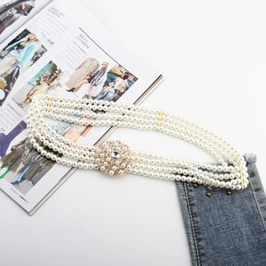 Close-up of a four-row pearl belt with a round gold rhinestone buckle on a blue denim