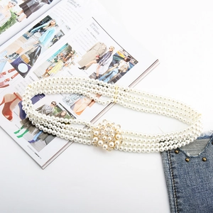 Close-up of three-row pearl belt with a vintage floral rhinestone buckle on denim