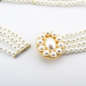 Detail of four-row pearl elastic belt with gold metal base and sparkling rhinestone inlay