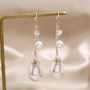 925 Silber Perlenohrringe mit Zirkonia auf eleganten goldenen Metallständern präsentiert